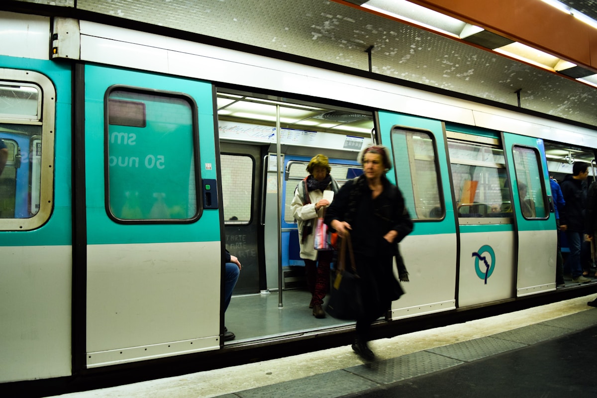 a group of people standing next to a train - Riding the Metro like a Parisian