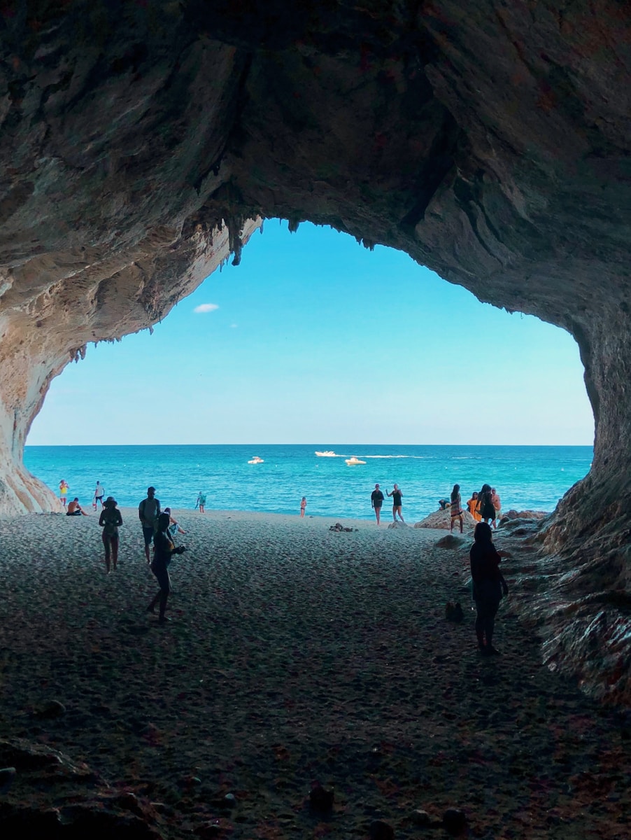 people standing front of sea at daytime - Sardinia Italy Travel Guide