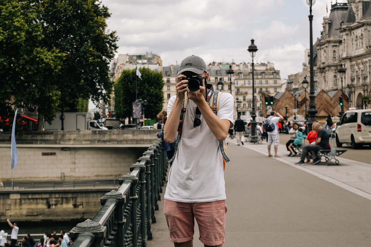 man holding DSLR camera beside bridge - Walking Tours in Paris