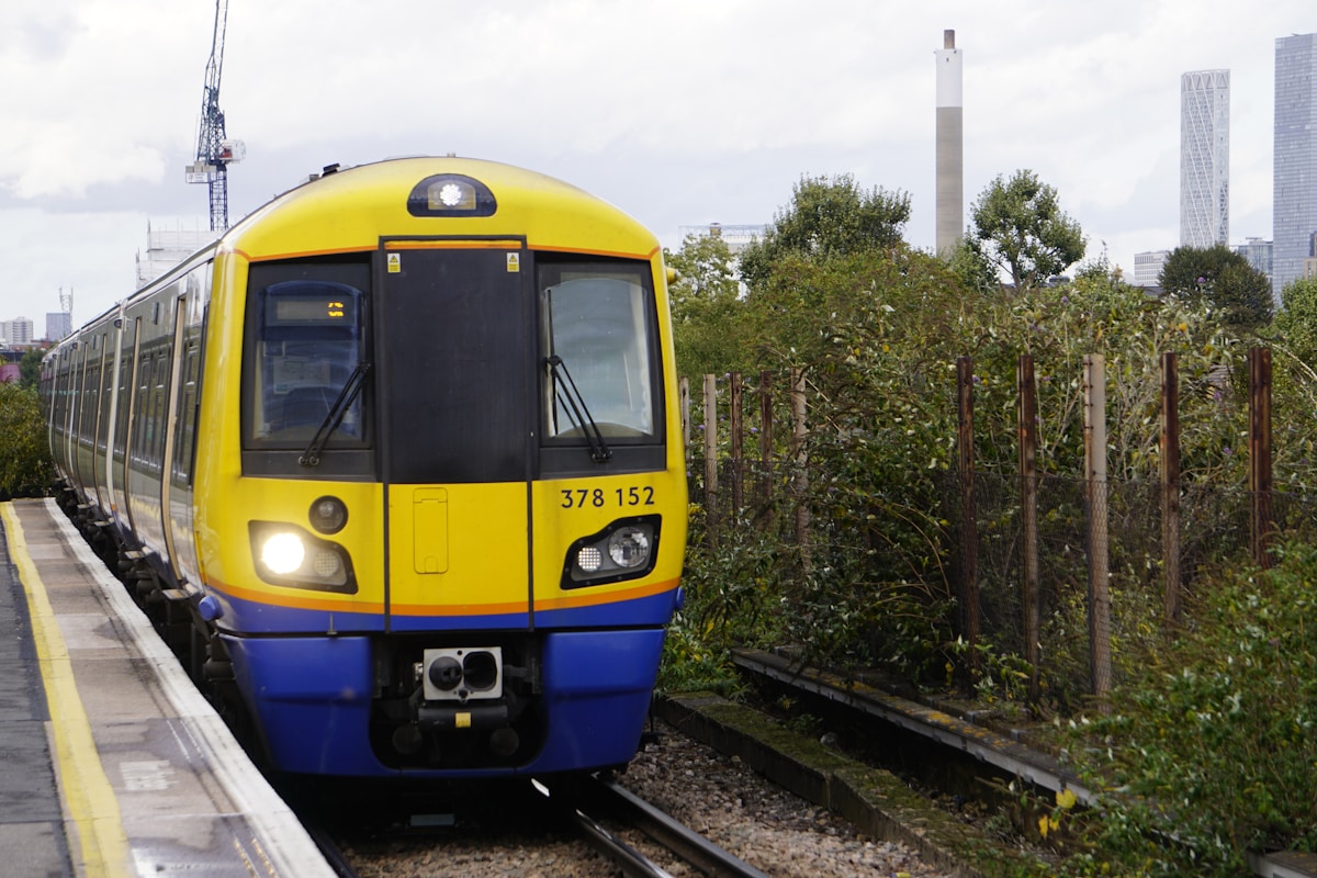 a yellow and blue train traveling down train tracks - London Transportation