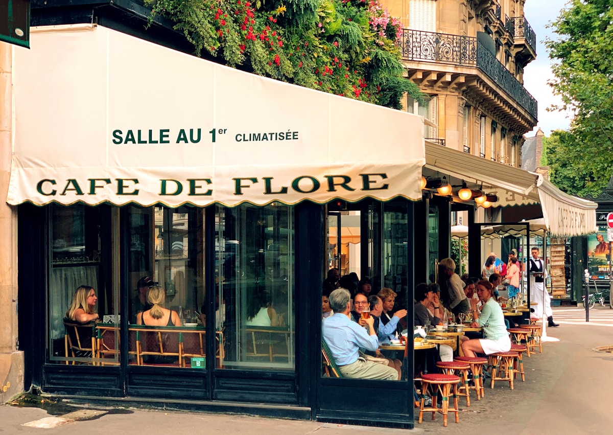 a group of people sitting outside of a cafe - Saint-Germain-des-Prés Paris