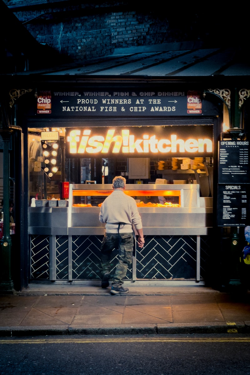 a man standing in front of a food stand - London Food