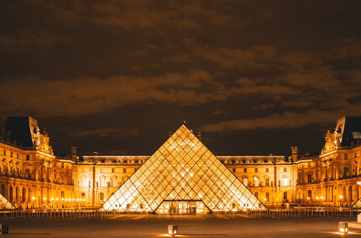 a very large building with a very tall pyramid in front of it - Louvre Paris