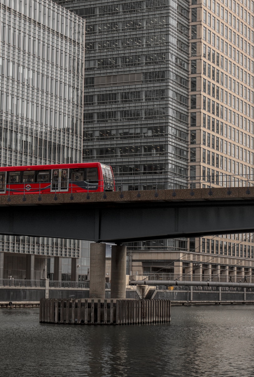 a red bus is crossing a bridge over a body of water - London Transportation