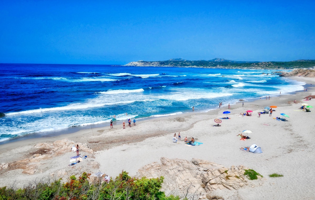 group of people on shore - Sardinia Italy Travel Guide