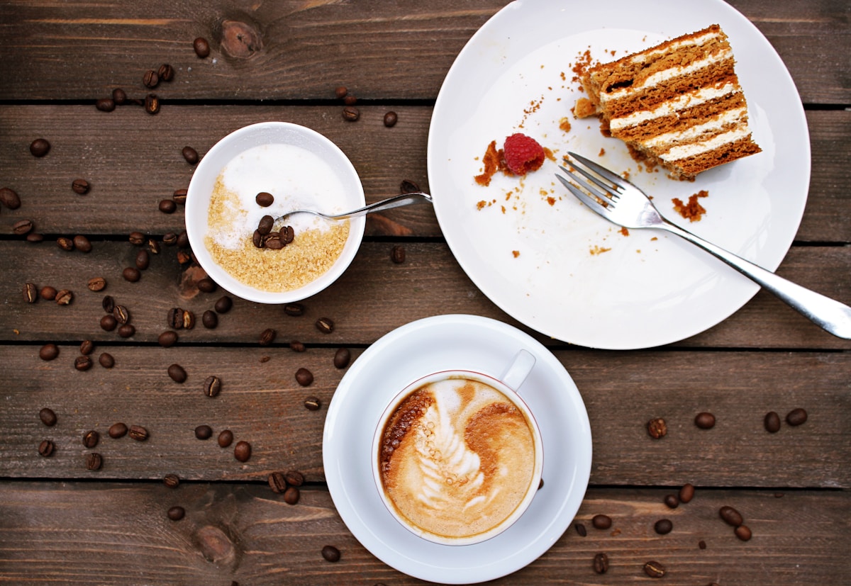 slice of cake on plate beside cappuccino - London Food