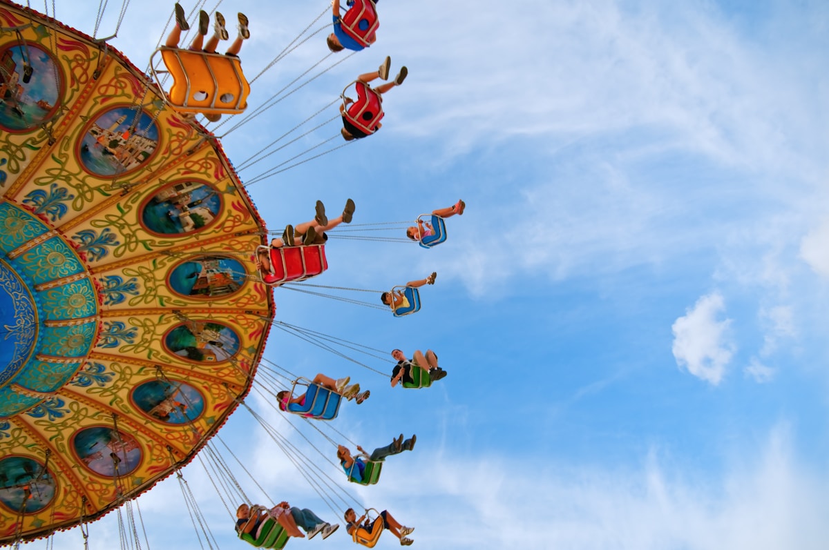 people riding carnival ride under blue skies - family trip to London top neighborhoods