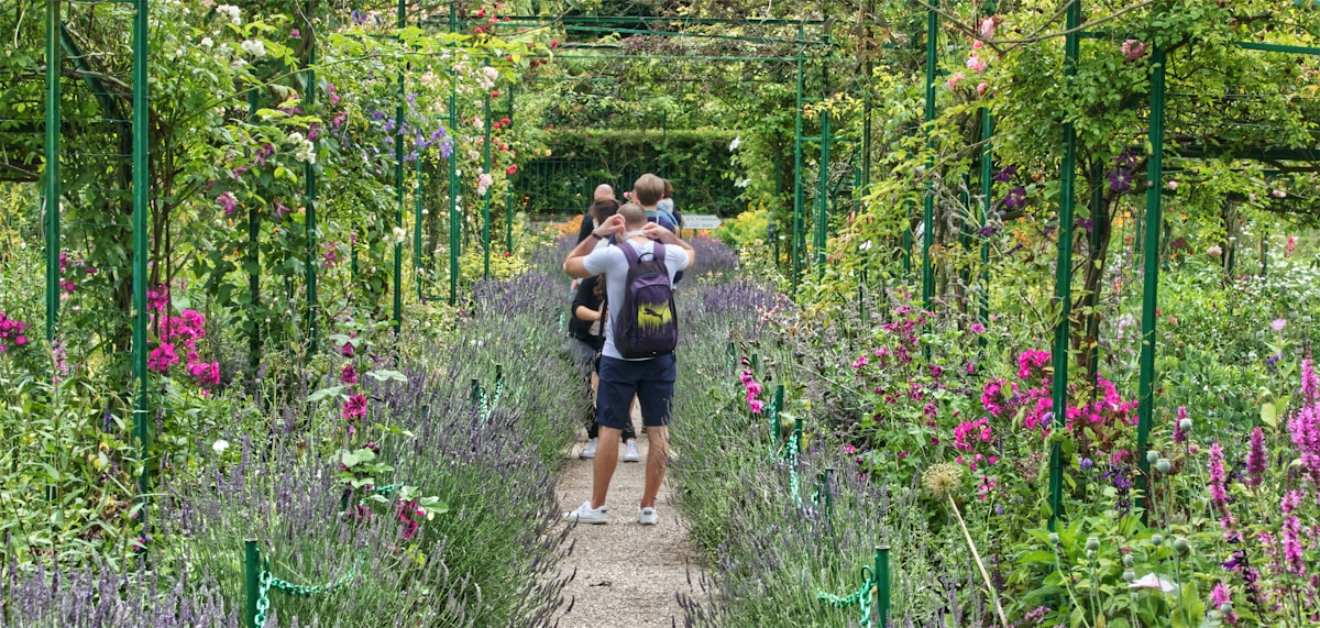 2 women walking on pathway surrounded by green plants during daytime - day trips from Paris