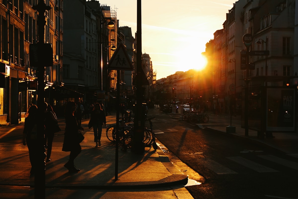 a group of people walking down a street next to tall buildings - Le Marais Paris