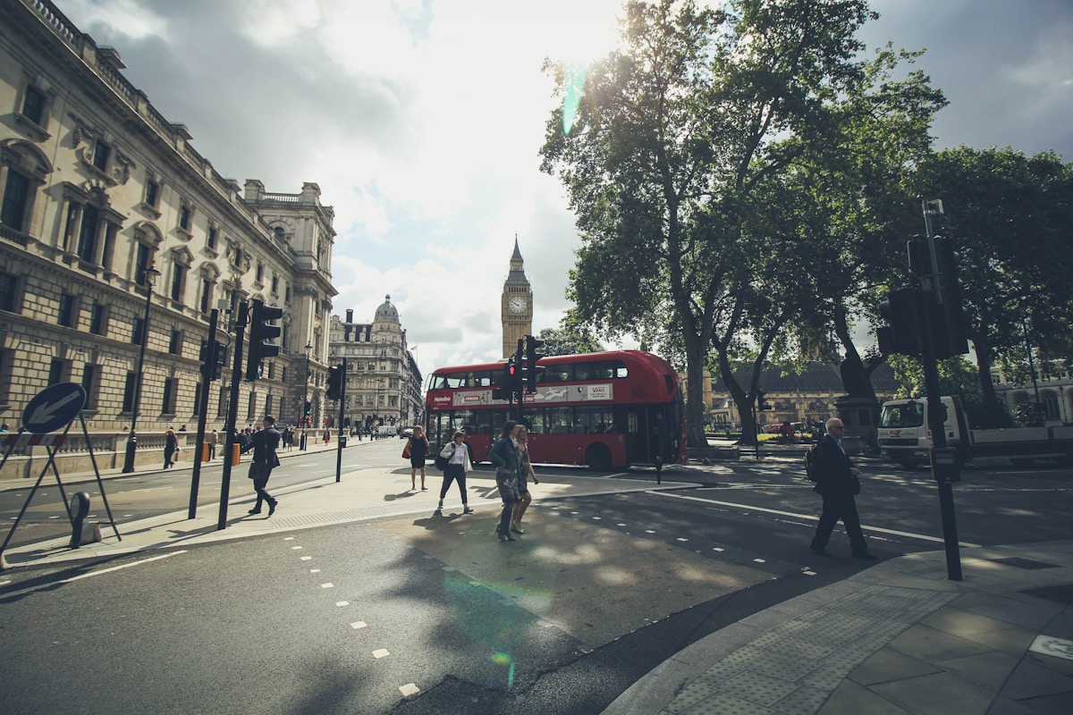 group of people walking on London road beside double deaker bus - family trip to London top neighborhoods