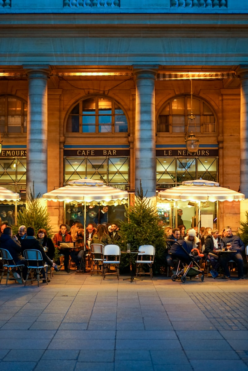 people eating beside building - food and wine guide Paris