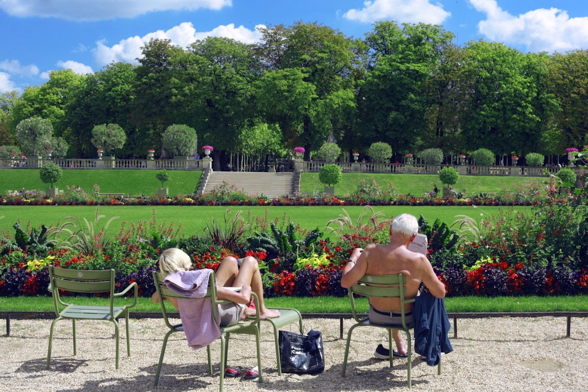 man sitting on green chair reading book - Family Trip to Paris