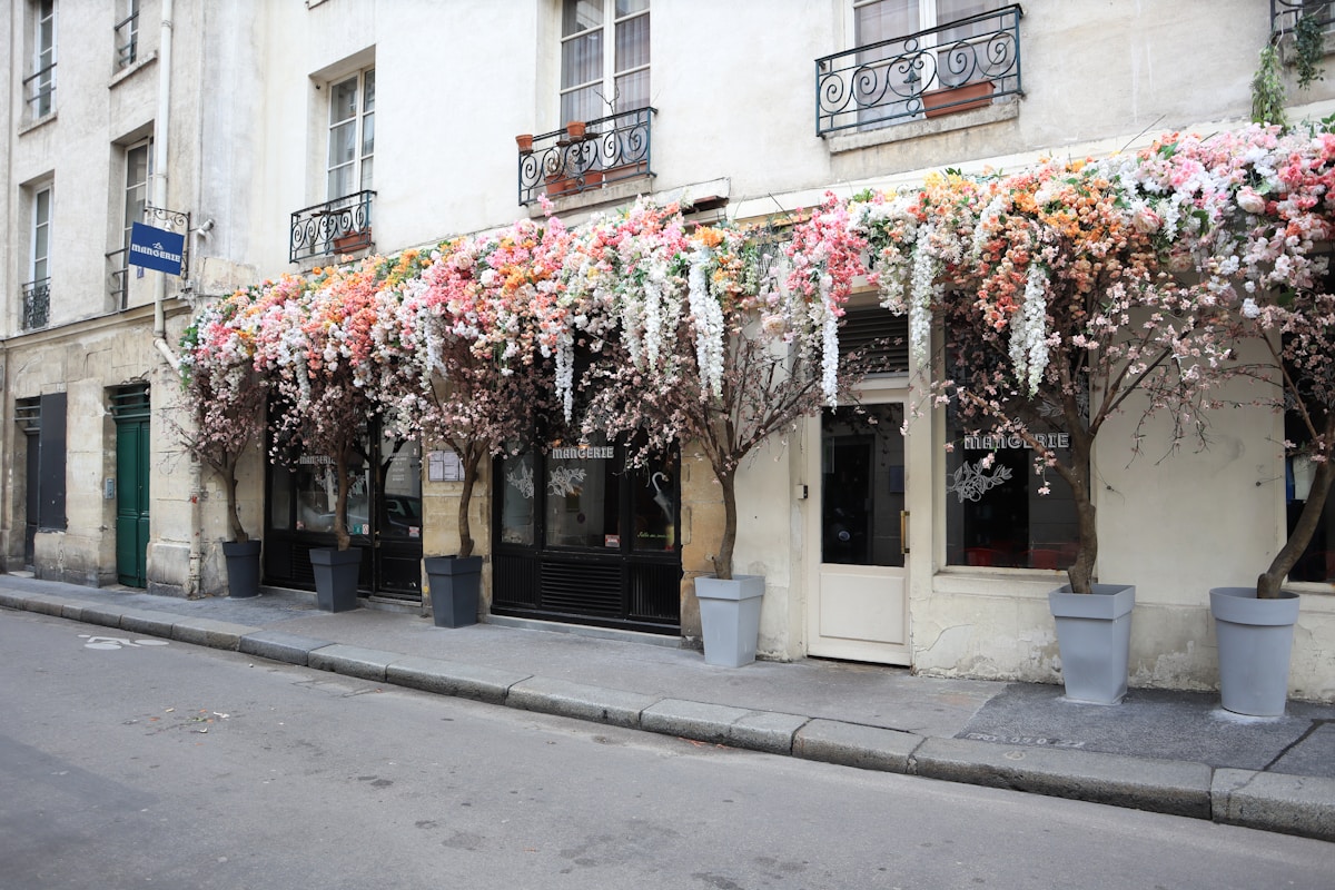 a building with a bunch of flowers on the outside of it - Marais Paris