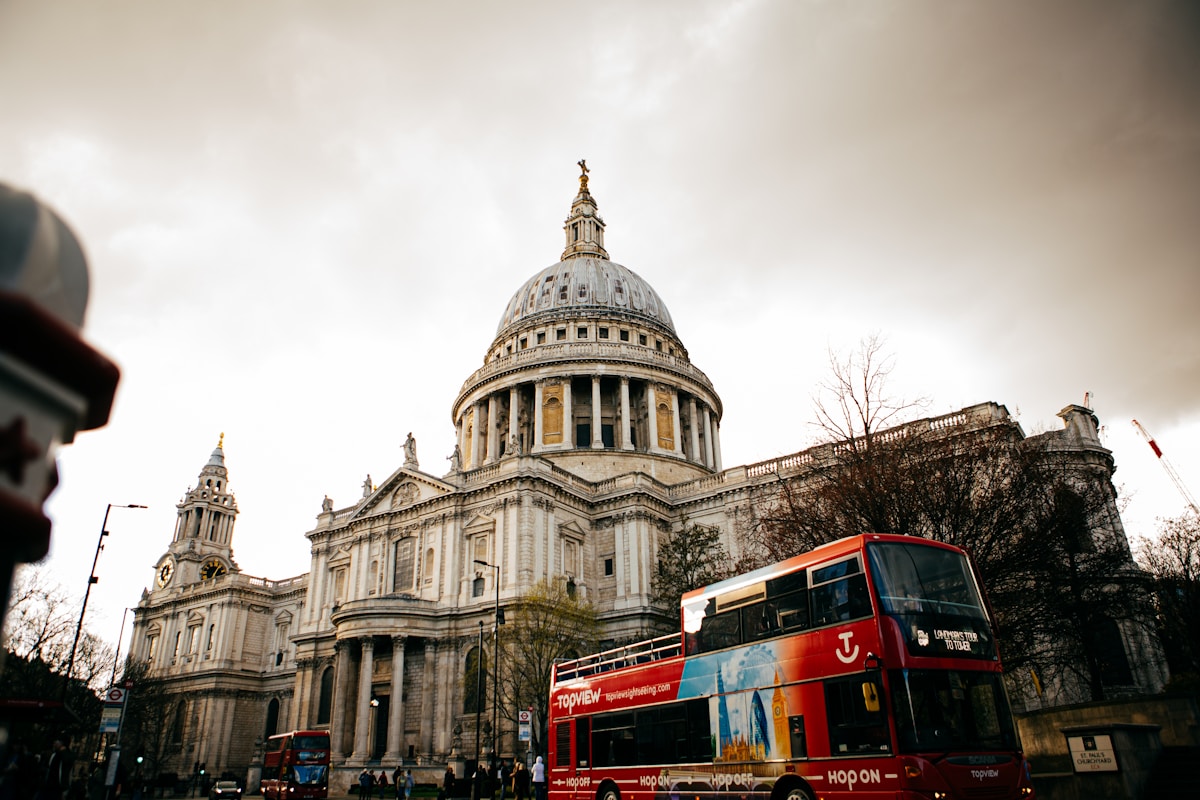 a red double decker bus parked in front of a building - London Transportation