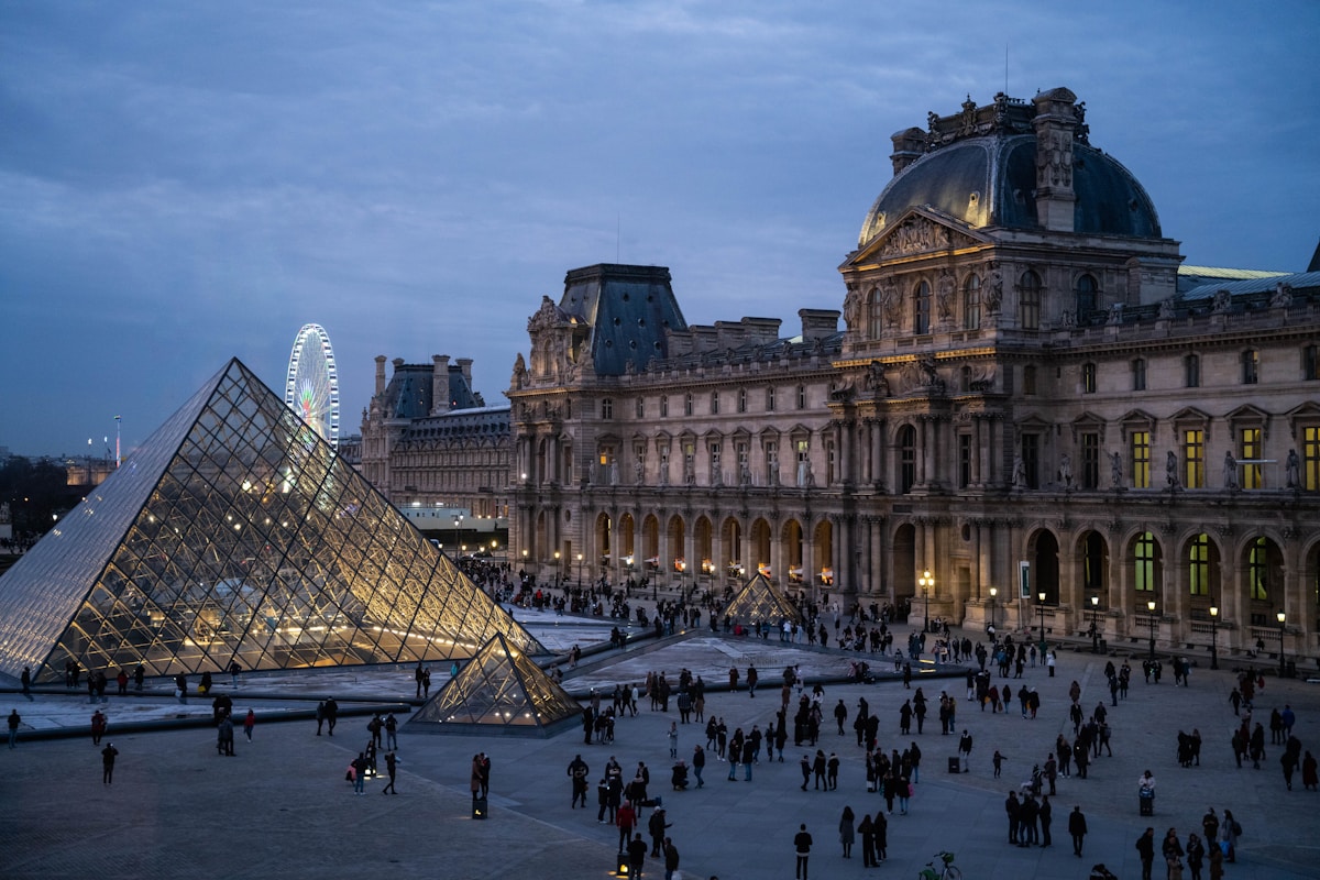 a group of people standing in front of Louvre Museum - Paris