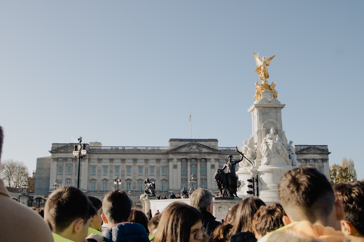 a crowd of people standing in front of a building - Buckingham Palace