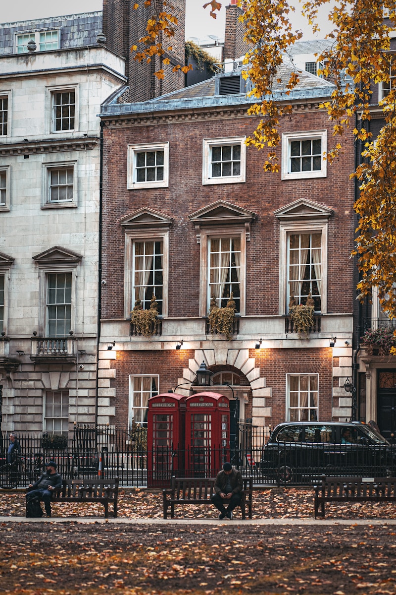 a red phone booth sitting in front of a tall building - Cultural Events and Festivals in London