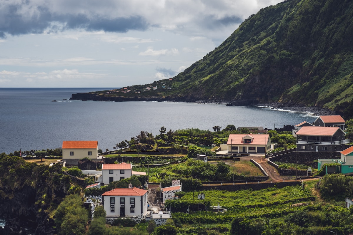 white and brown concrete houses near body of water during daytime - São Jorge Azores Portugal