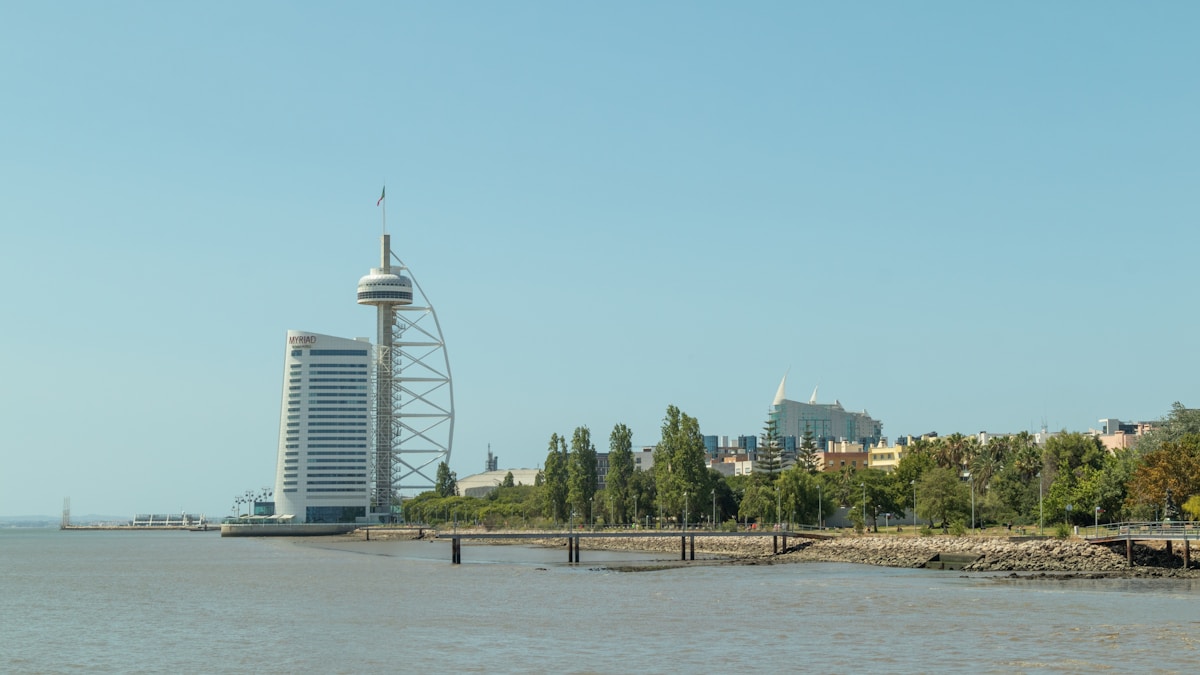 a large body of water with a tall building in the background - Parque das Nações, Lisboa, Portugal