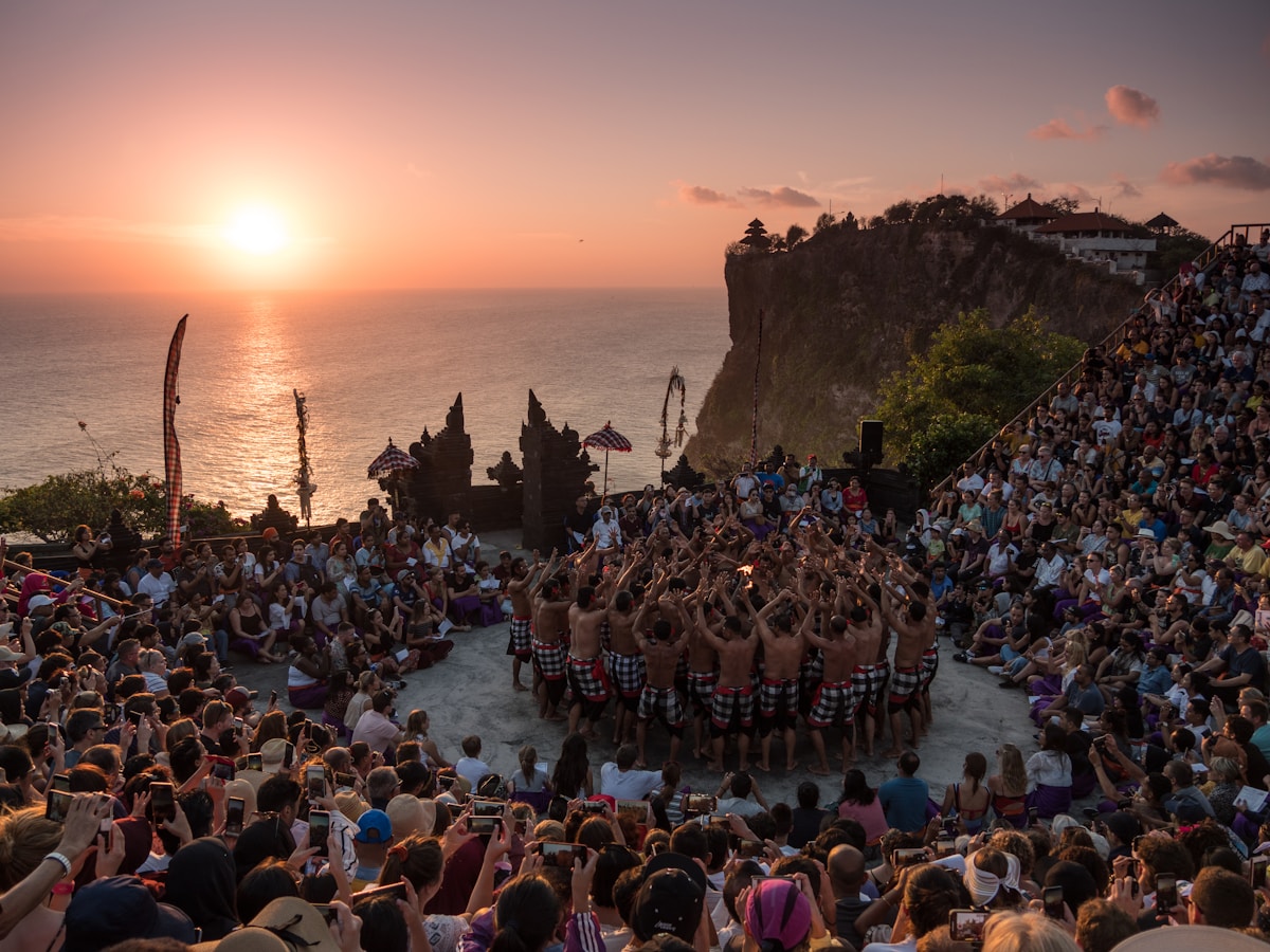 Things to do in Uluwatu - Watchin Kecak Dance - people standing on brown rock formation near body of water during sunset