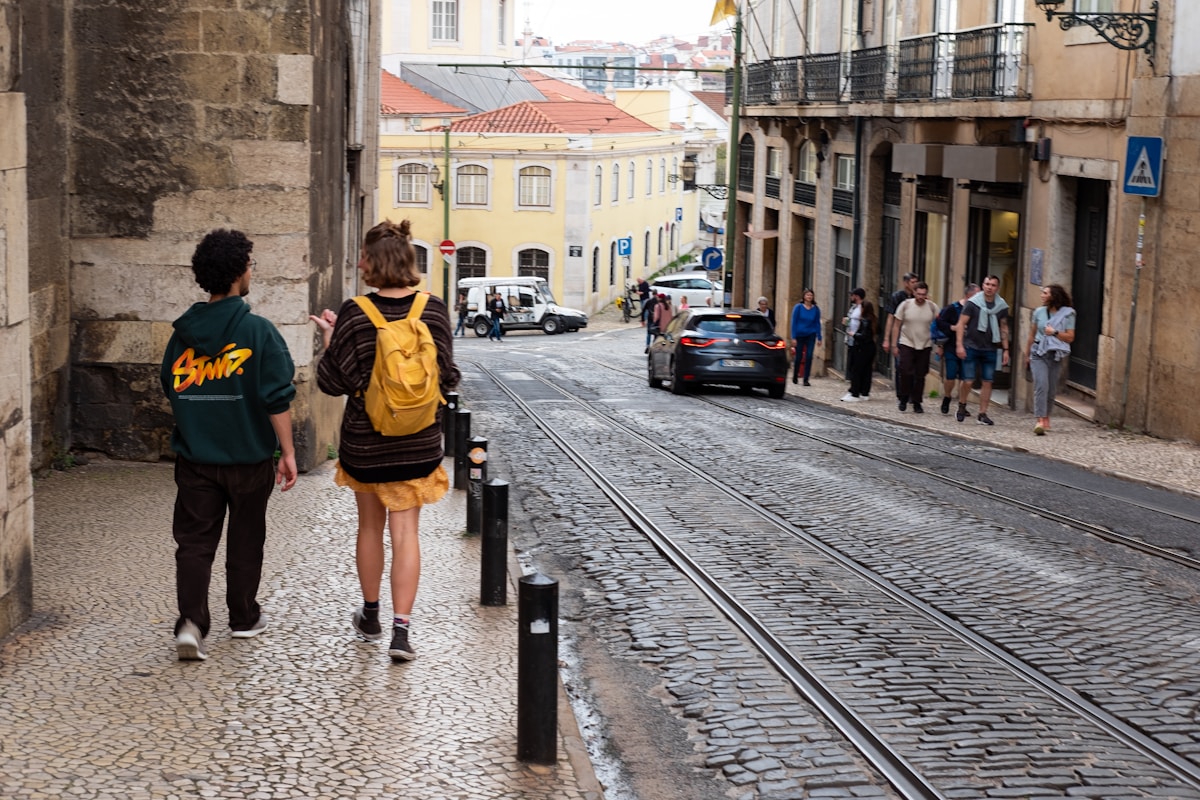 A couple of people that are walking down a street - Walking tour Lisbon, Portugal