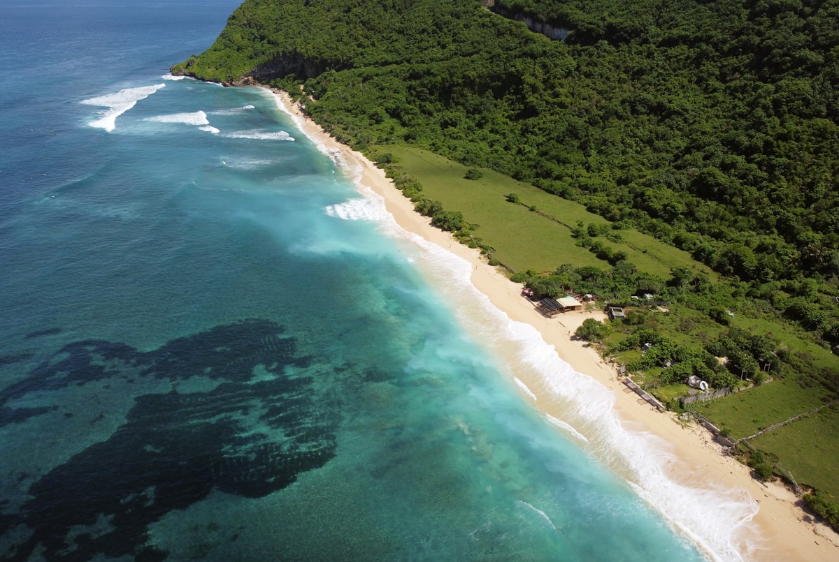 an aerial view of a beach and a forested area - Nyang-Nyang Beach Uluwatu Bali