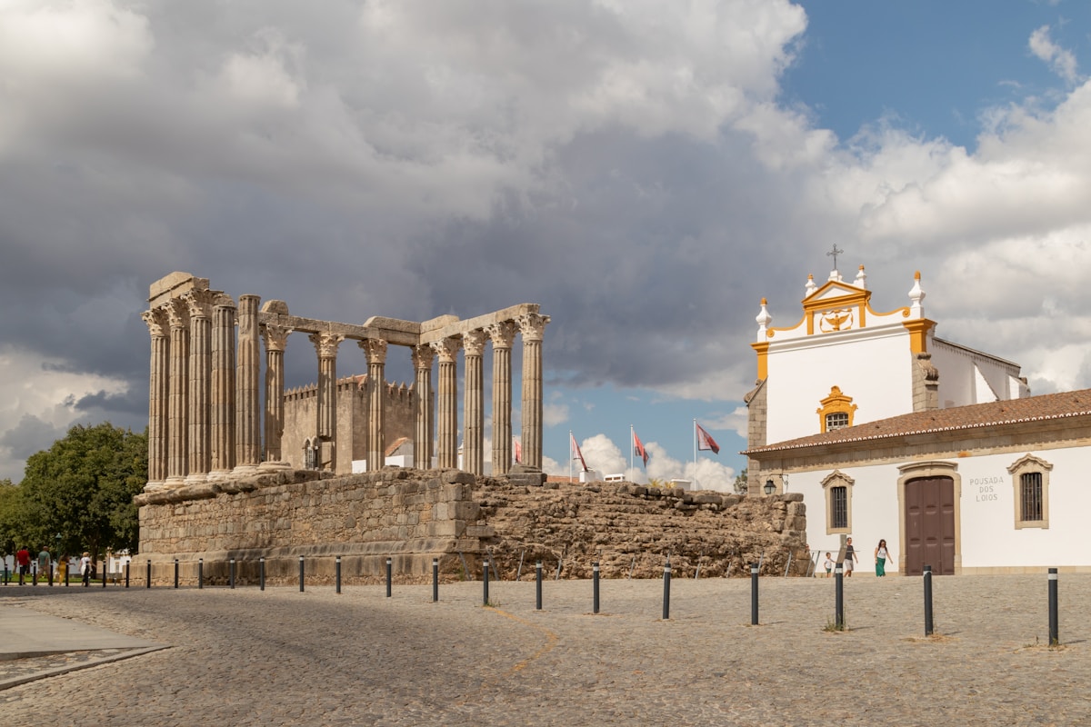 a large building with columns and a clock tower - Templo Romano de Évora, Lisbon, Portugal