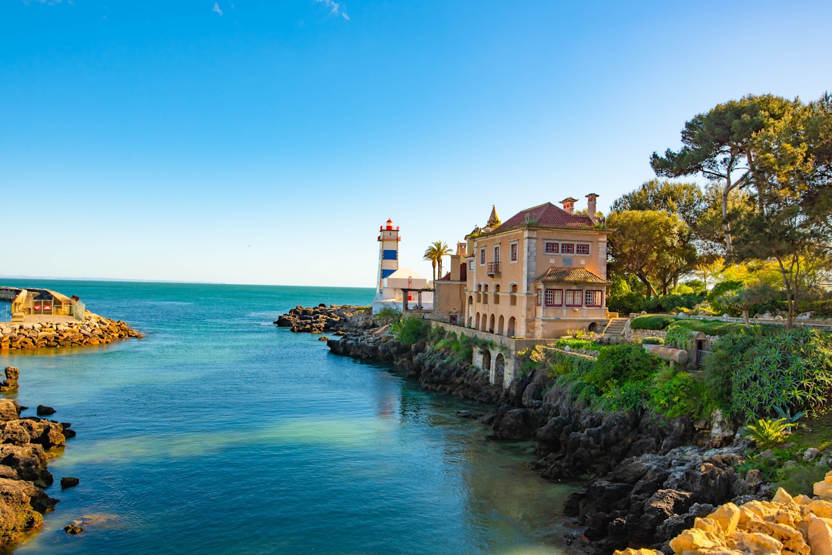 white and brown concrete building beside body of water during daytime - Cascais beach, Lisbon, Portugal