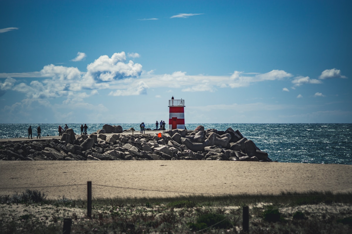 a red and white lighthouse sitting on top of a sandy beach - Nazaré Lighthouse, Lisbon, Portugal