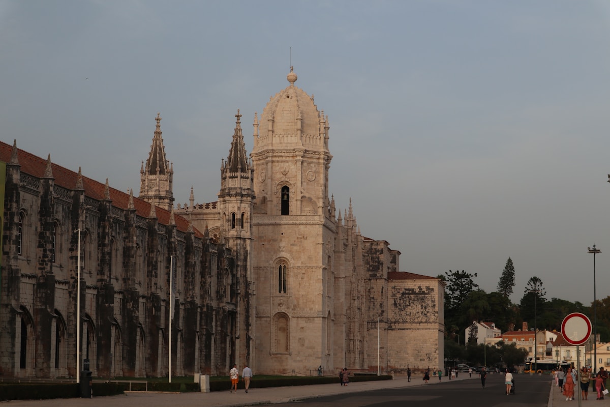 a very tall building with a clock on it's side - Mosteiro dos Jerónimos, Lisbon, Portugal