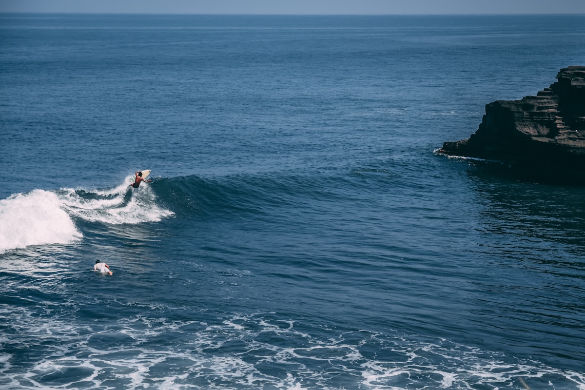 man surfing on sea during daytime in Uluwatu, Bali