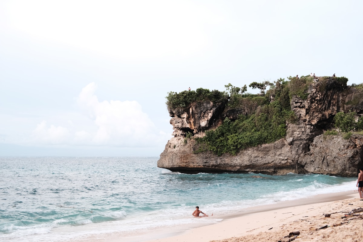 a couple of people standing on top of a sandy beach - Balangan Beach Uluwatu Bali