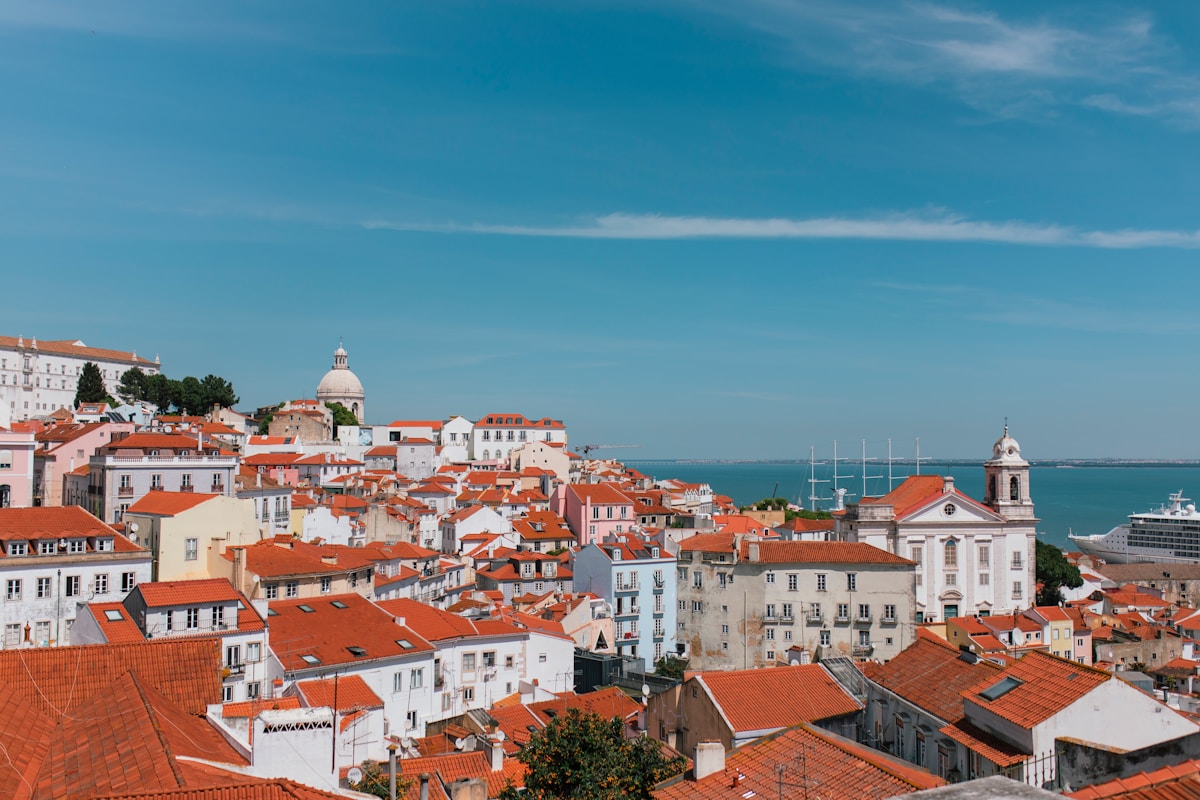 a view of a city with a cruise ship in the background - Miradouro das Portas do Sol Lisbon, Portugal