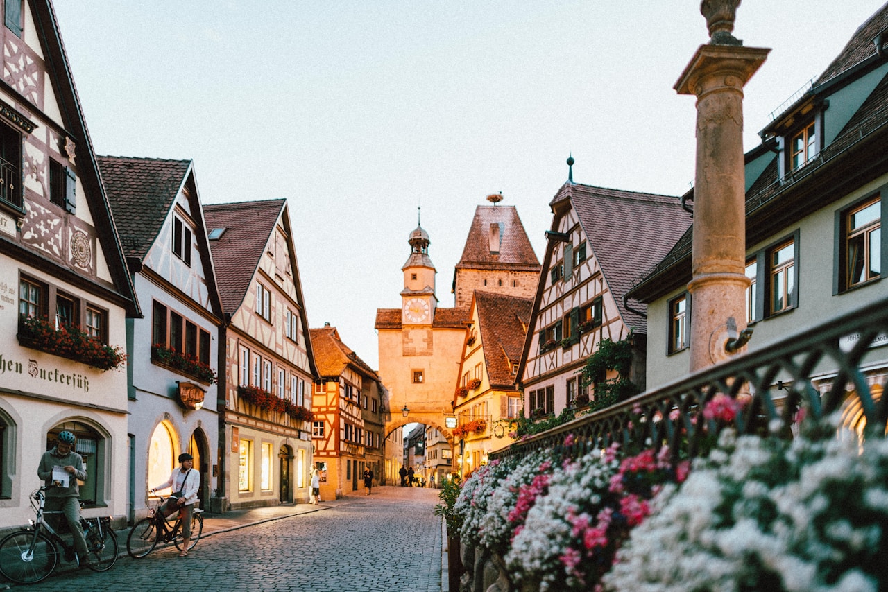 Best Day Trips From Munich, white and pink petaled flowers on metal fence near concrete houses and tower at daytime