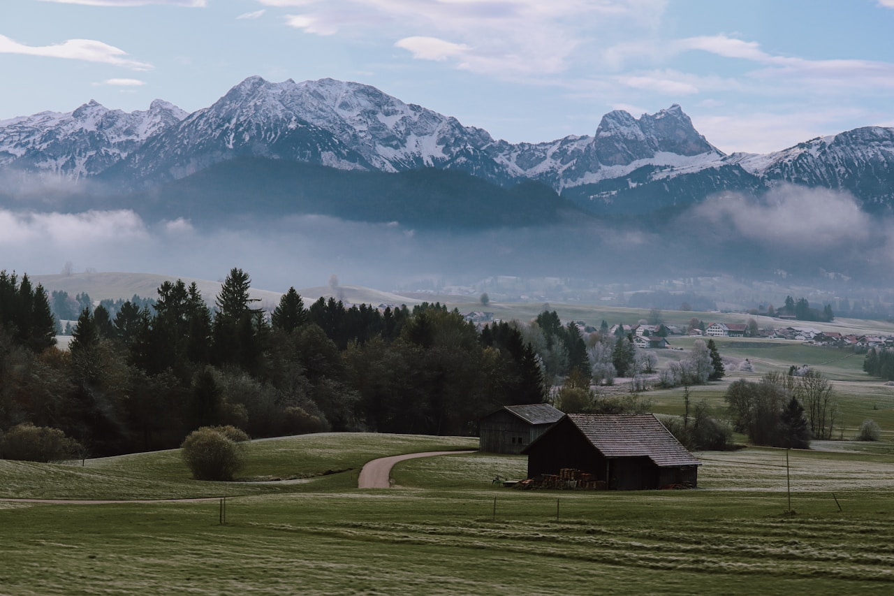 Best Day Trips From Munich, a barn in a field with mountains in the background