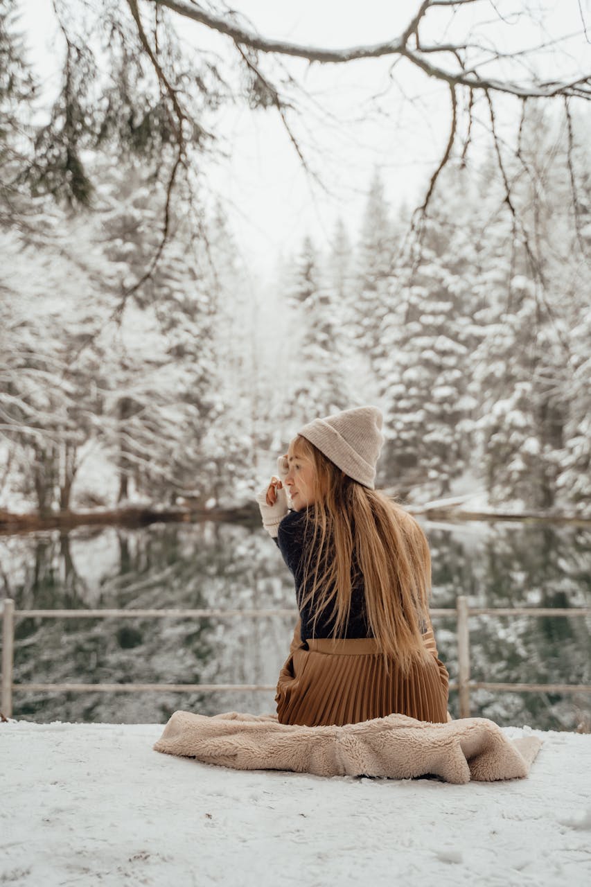 Best Time to Visit Munich, A woman enjoying the serene winter landscape by a snow-covered forest lake.
