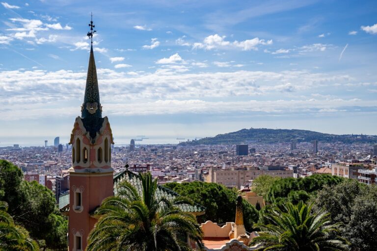 Barcelona skyline featuring a colorful tower against a backdrop of the sea and clouds, highlighting the city's architectural beauty.