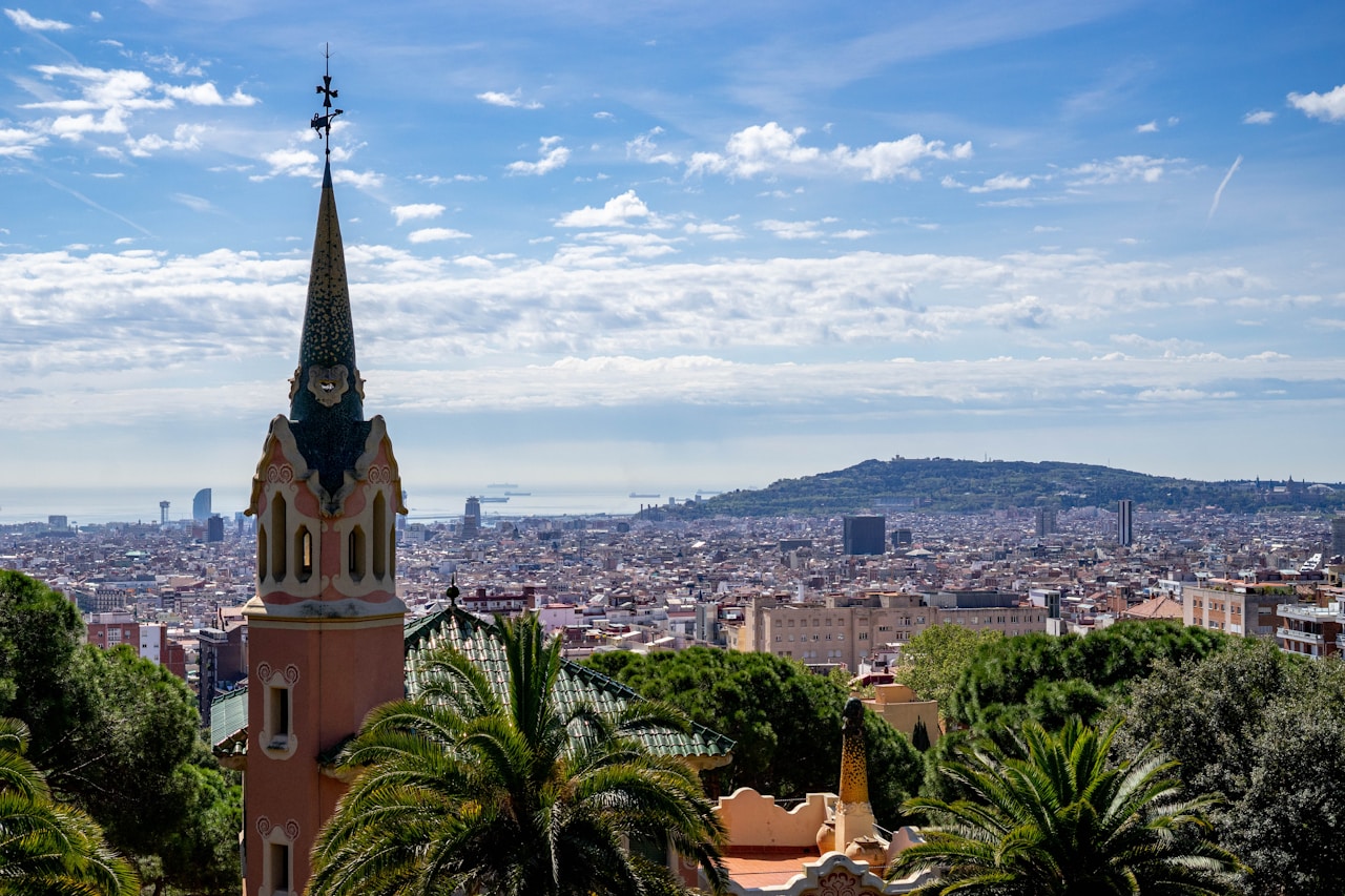 Barcelona skyline featuring a colorful tower against a backdrop of the sea and clouds, highlighting the city's architectural beauty.