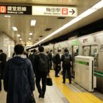 Crowded Umeda Station in Osaka, with commuters boarding the Midosuji Line subway amidst a bustling urban atmosphere.
