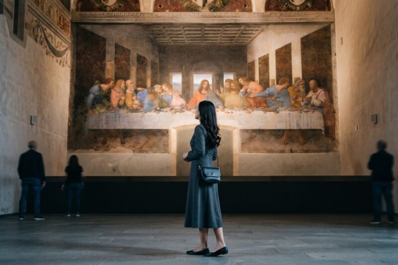 Kannaya Nareswari admiring Leonardo da Vinci's "The Last Supper" mural in a serene museum setting, surrounded by other visitors.