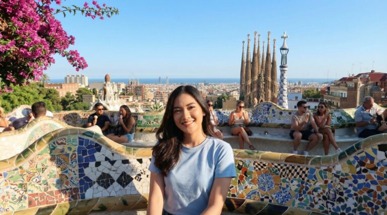 Smiling Kannaya Nareswari at Park Güell in Barcelona, surrounded by vibrant mosaic tiles and views of the city and sea.