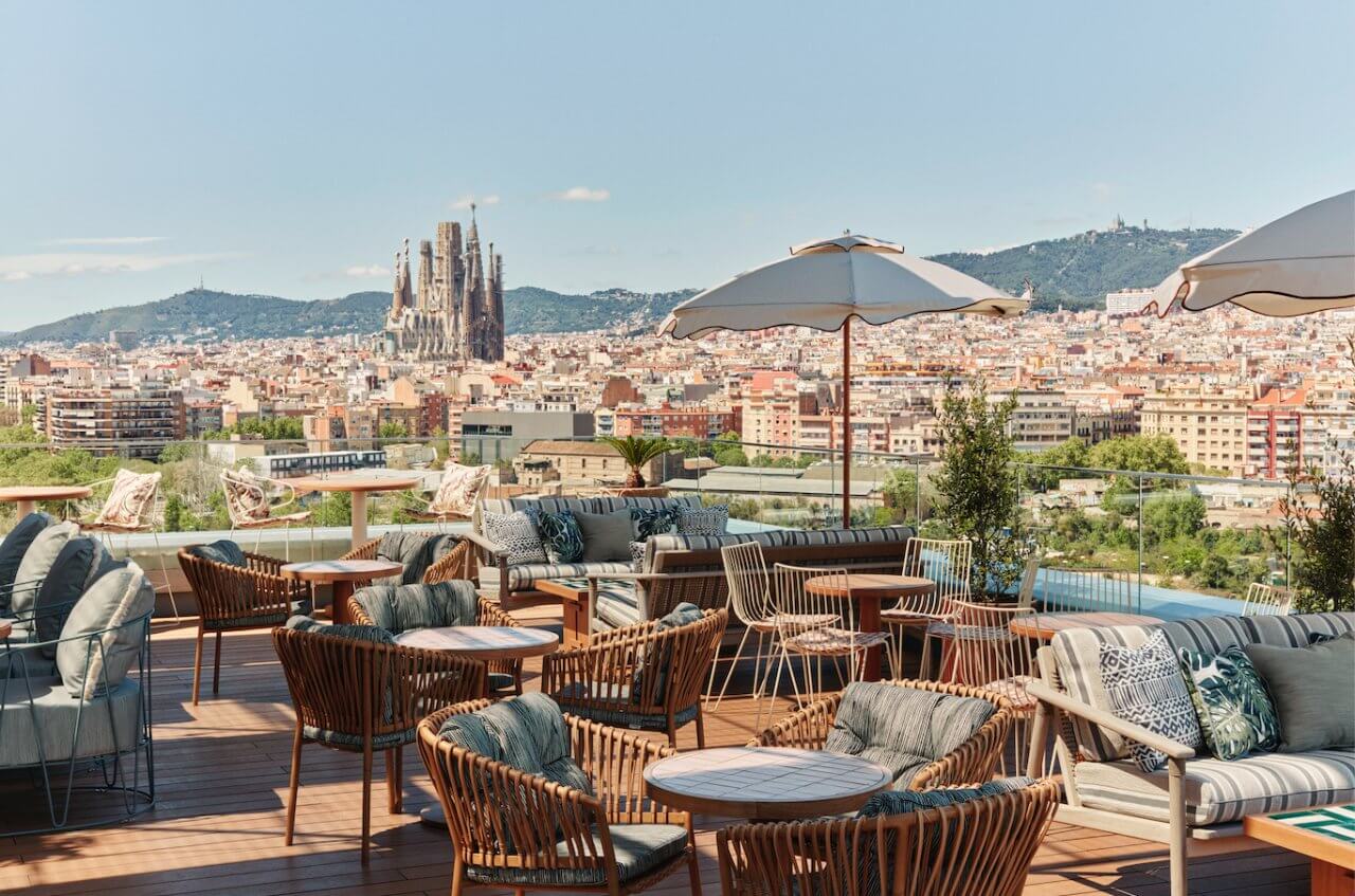 Rooftop terrace in Barcelona featuring cozy seating and a stunning view of the Sagrada Família and city skyline.