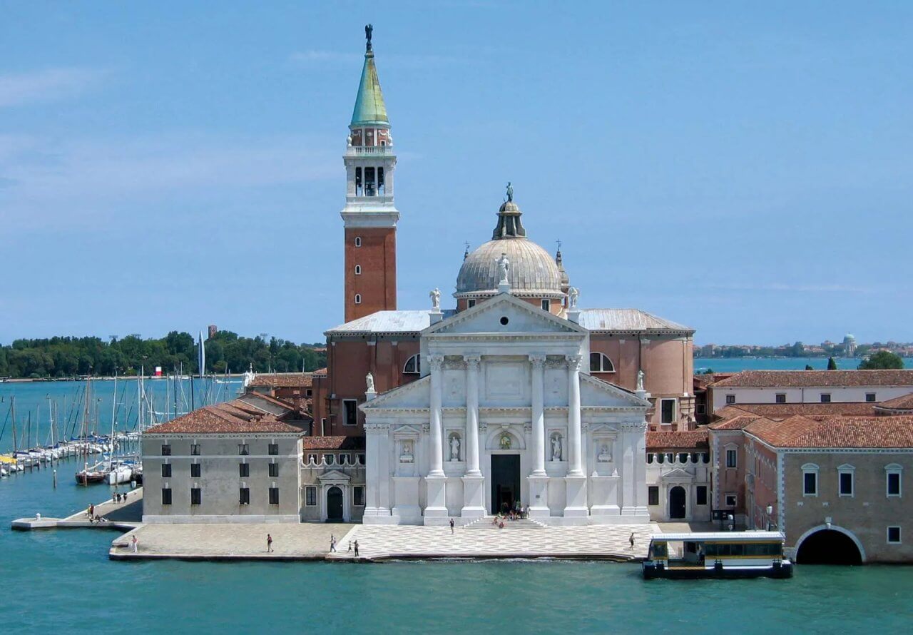 Historic San Giorgio Maggiore church in Venice overlooking serene waters with sailboats, showcasing stunning architecture and vibrant surroundings.