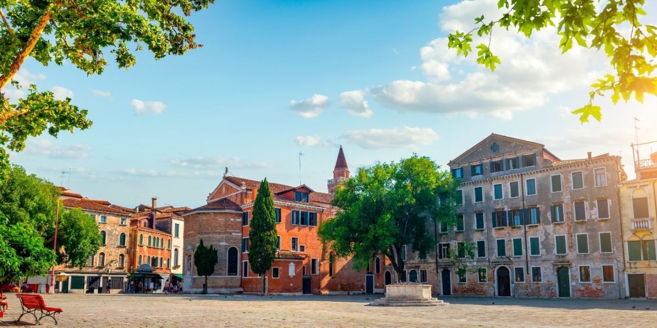 Charming Venetian square at San Polo with historic buildings, greenery, and a vibrant sky, perfect for leisurely strolls and exploration.