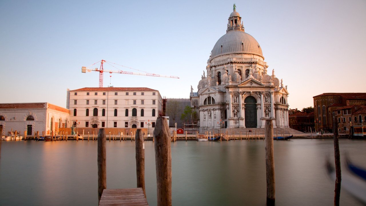 Santa Maria della Salute in Venice reflecting sunset hues, showcasing stunning baroque architecture by the water's edge.