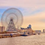 Ferris wheel towering over a scenic riverside promenade, capturing the vibrancy of urban life and waterfront leisure.