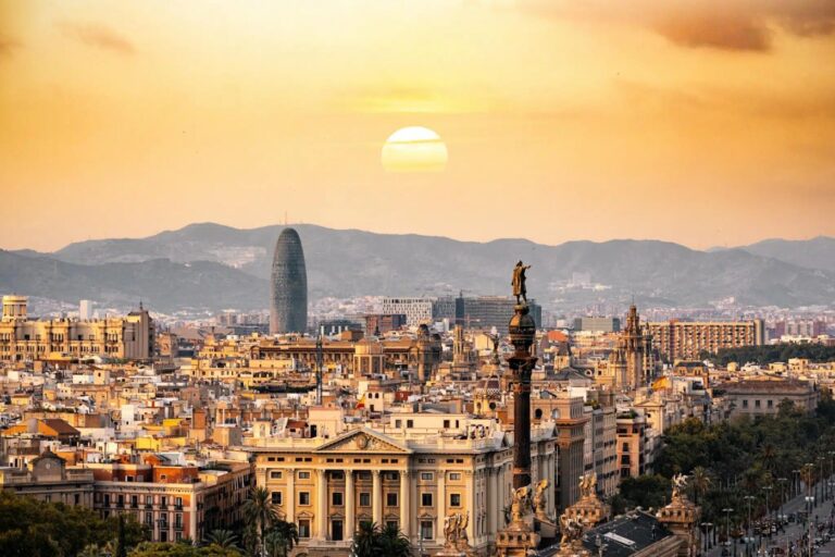 Sunset over Barcelona showcasing historic architecture and modern skyline, with the iconic Columbus Monument in view.
