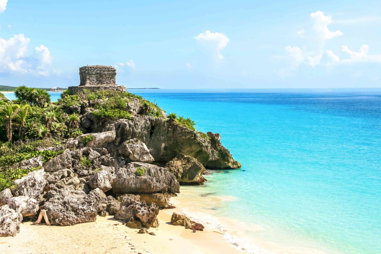Tulum's ancient ruins overlooking the Caribbean Sea, with sandy beach and turquoise waters, evoke a sense of tropical paradise.