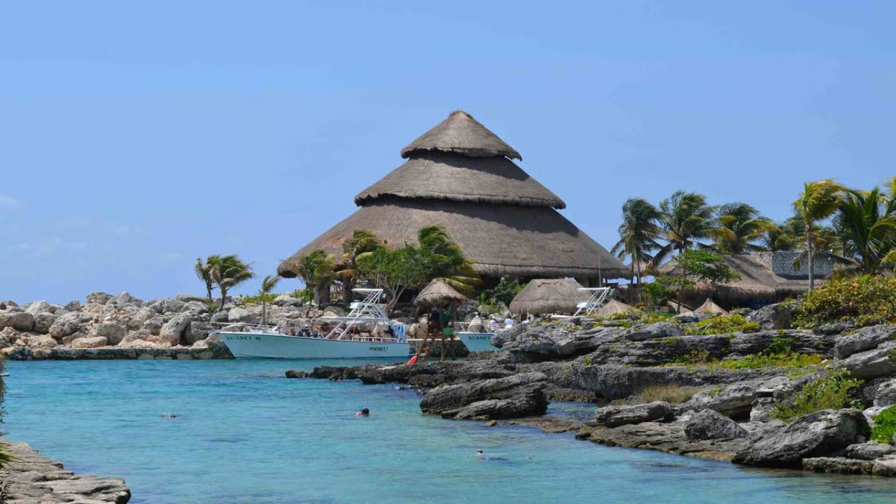 Tropical beach scene featuring a thatched-roof restaurant by the turquoise water, perfect for relaxation and dining.