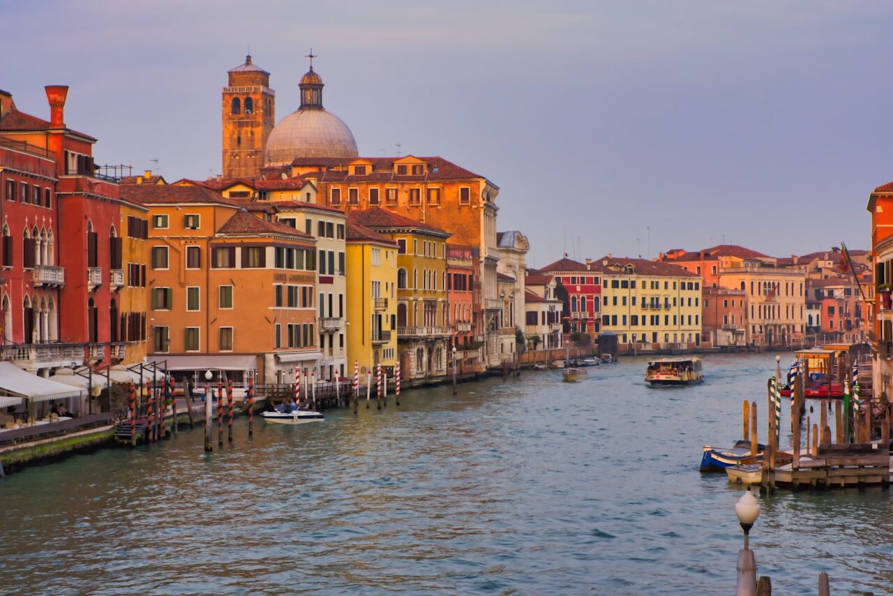 Venetian canal adorned by colorful historic buildings, capturing the charm of Venice's vibrant waterfront at sunset.